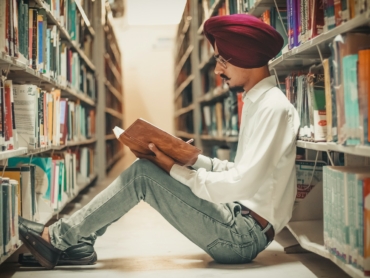 man sitting in front of bookshelf