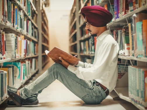 man sitting in front of bookshelf