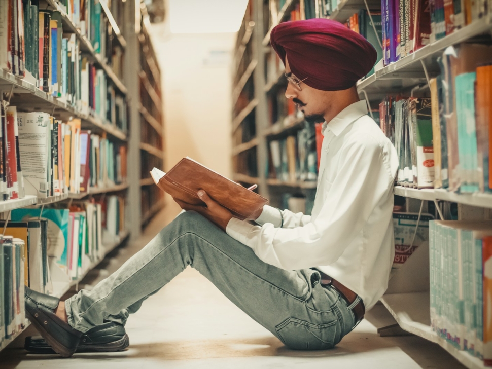 man sitting in front of bookshelf