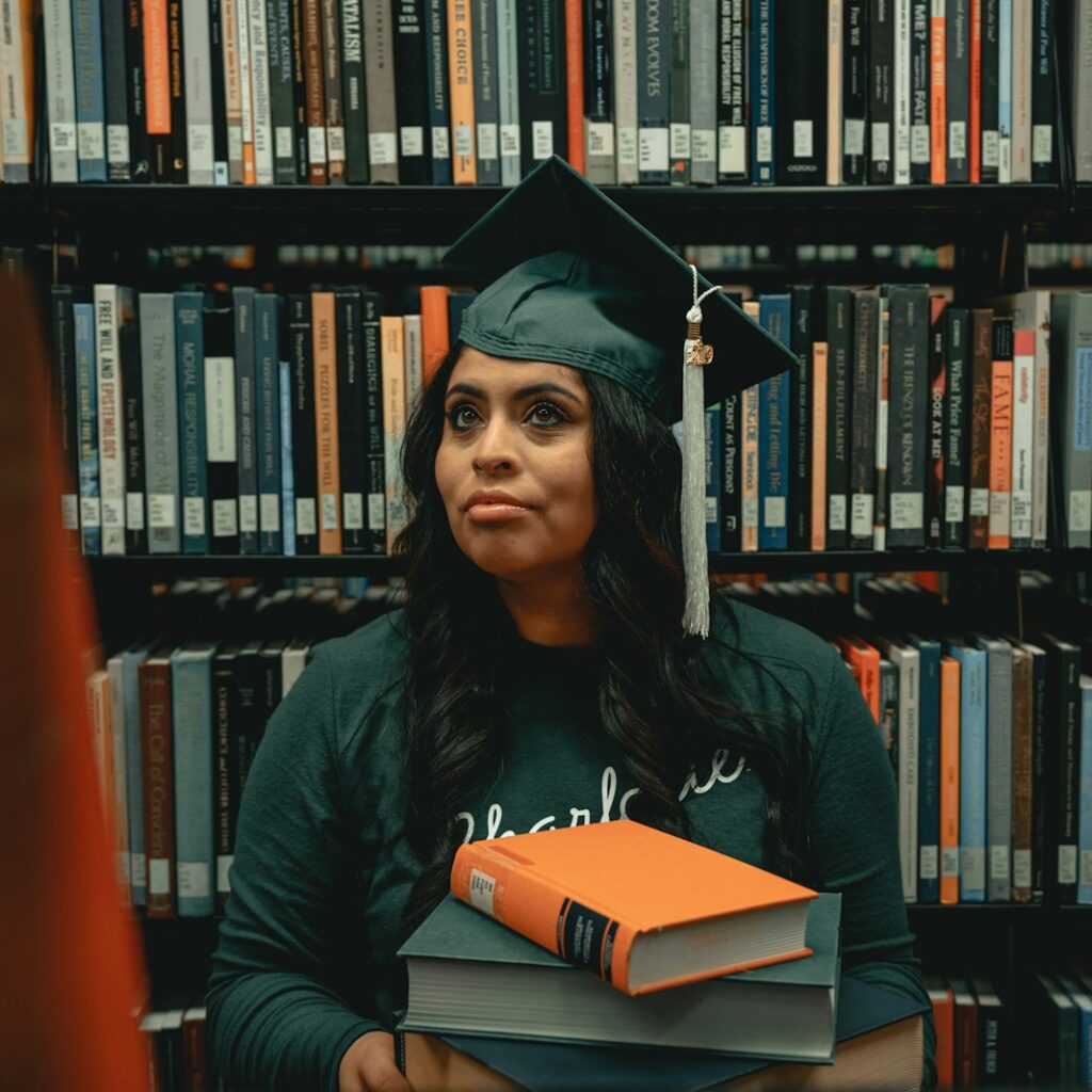 a woman in a cap and gown holding a stack of books