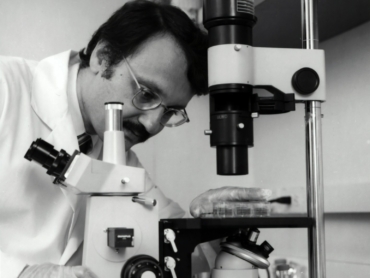 grayscale photography of doctor using microscope
