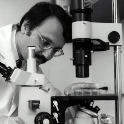 grayscale photography of doctor using microscope