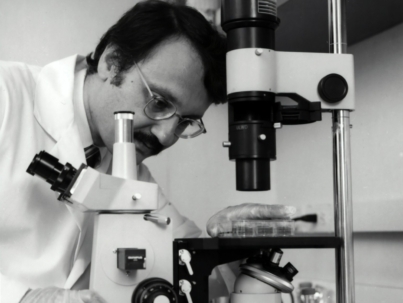 grayscale photography of doctor using microscope